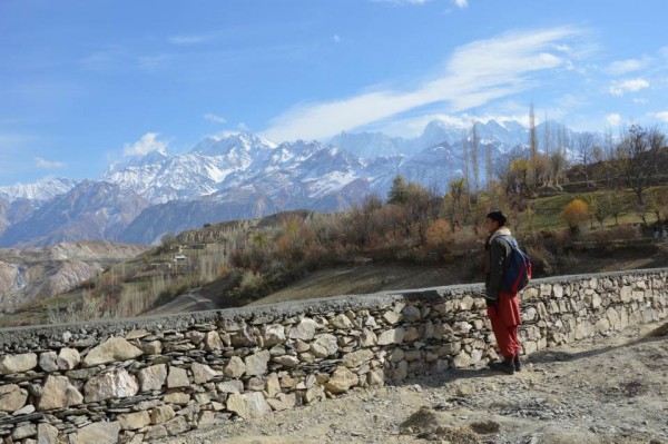 A boy looks at the snow-capped Hindu-Kush mountain peaks in flood-prone Bindo Gol valley in Pakistan's Chitray district, while standing near a flood protection wall. TRF/Saleem Shaikh
