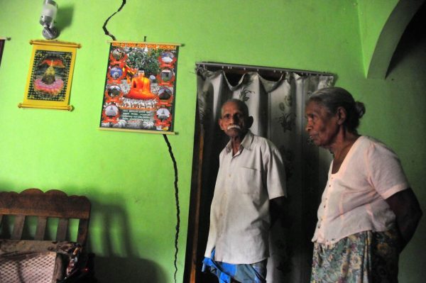 The Karunadasa family stand in their living room, near a crack in their wall that first appeared on May 17, a night when landslides claimed 130 lives in a neighbouring area, and that has been slowly widening since. TRF/Amantha Perera